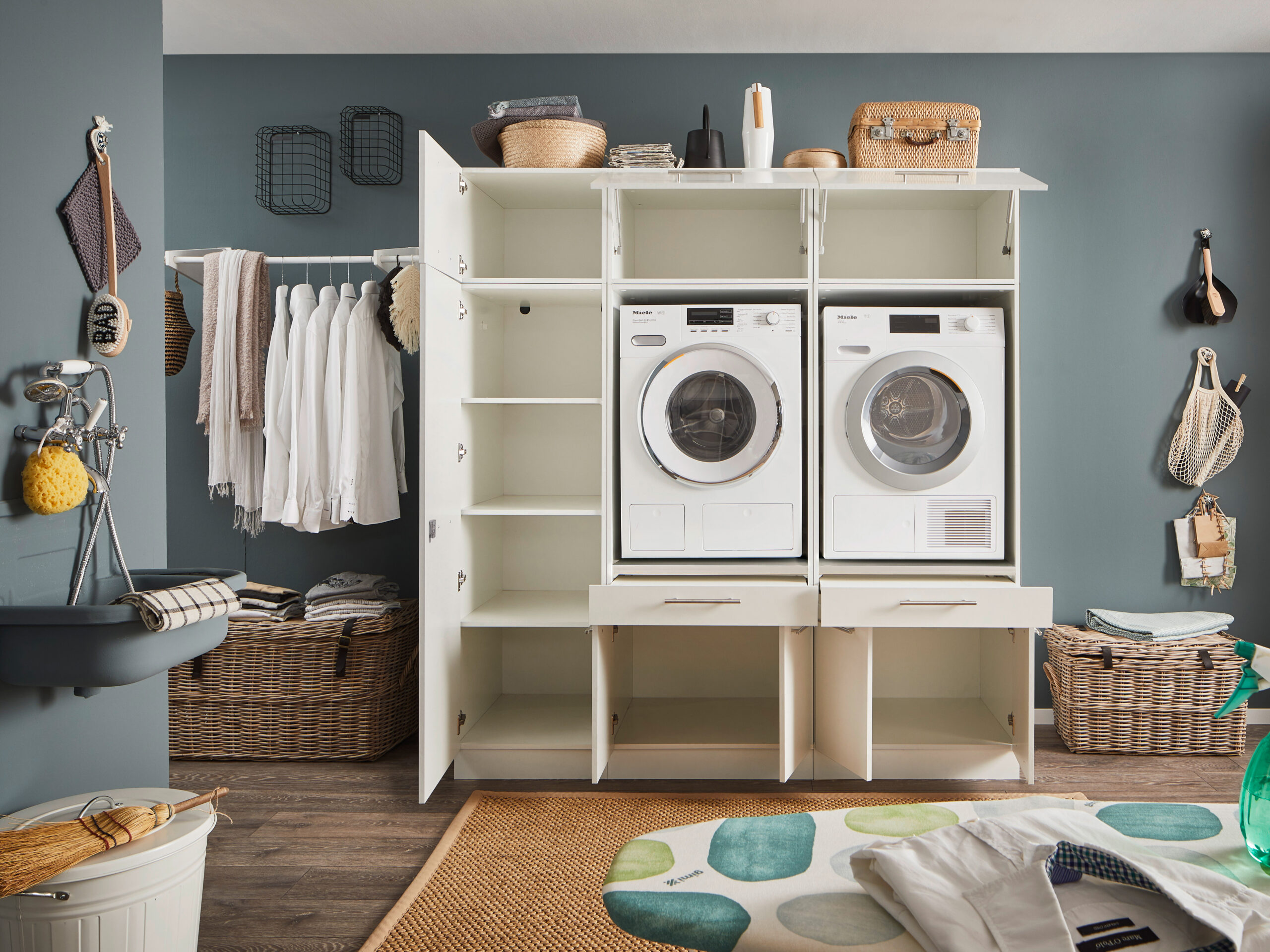 Offene weiße Schranklösung mit integriertem Waschmaschinen Turm und großzügigen Staufächern im Hauswirtschaftsraum.
