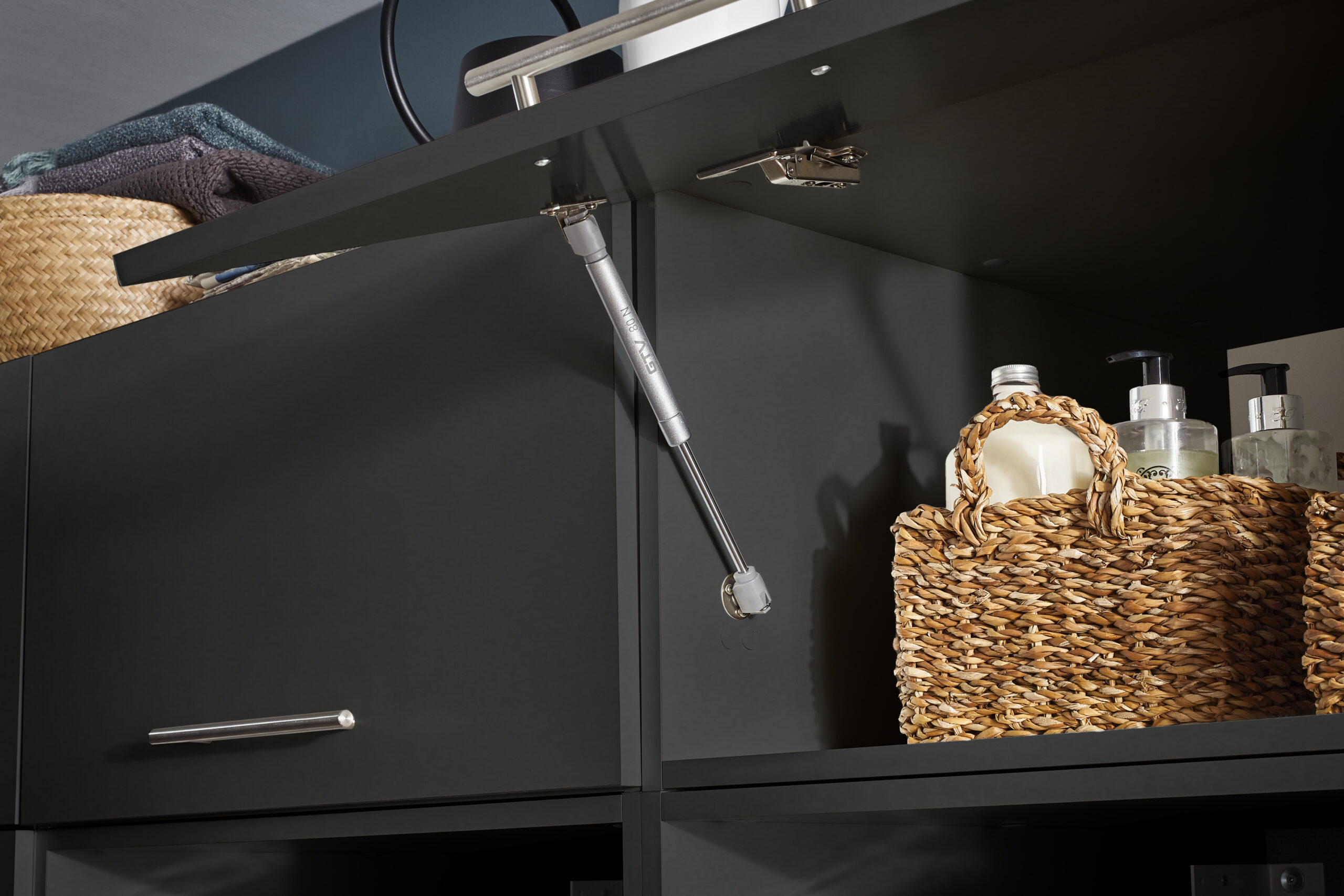 Geöffnete Schrankklappe mit Gasdruckdämpfer und aufgeräumtem Innenraum.