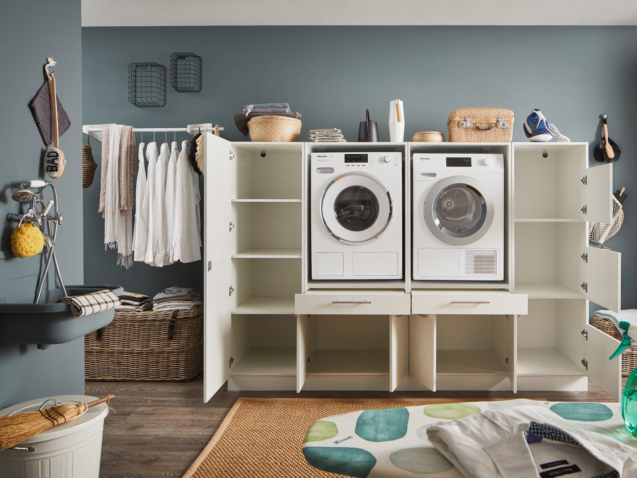 Geöffnete weiße Waschmaschinen Schranklösung mit sichtbaren Fächern und integriertem Waschmaschinen Duo in modernem Waschraum.