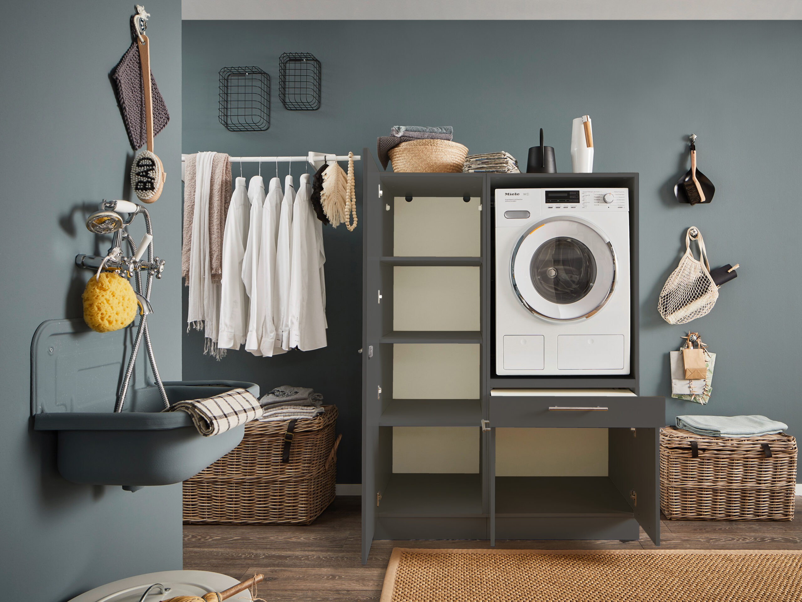 Offener Waschmaschinen Schrank in Anthrazit mit mehreren Fächern in moderner Waschküche.