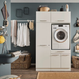 Ein Waschraum mit eingebauter Waschmaschine in einem weißen Möbelmodul, Kleiderstange mit weißen Hemden, Körben und einem Wandwaschtrog.