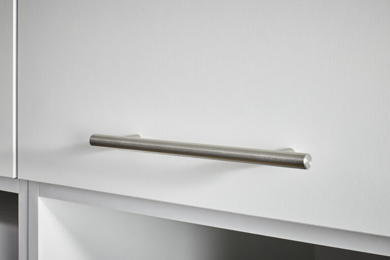 Detailaufnahme eines schlichten Metallgriffs an einer weißen Schrankfront.