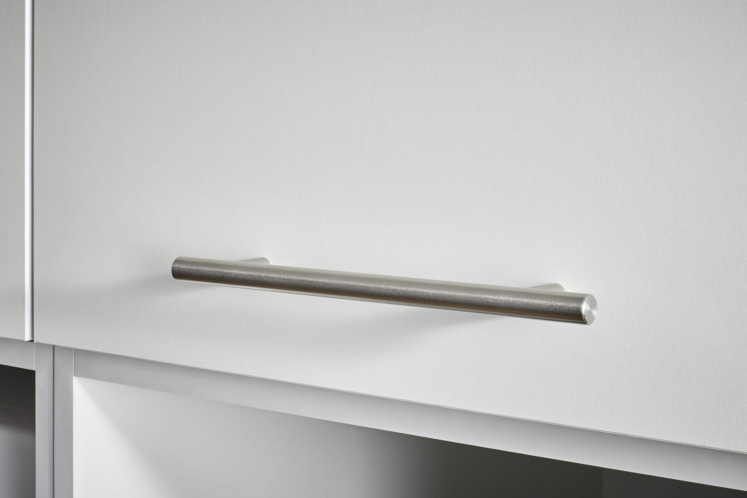 Detailaufnahme eines schlichten Metallgriffs an einer weißen Schrankfront.